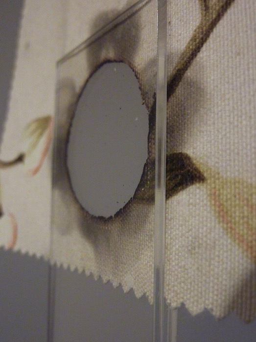 (p)Reserve — Close up of burnt textile piece & perspex