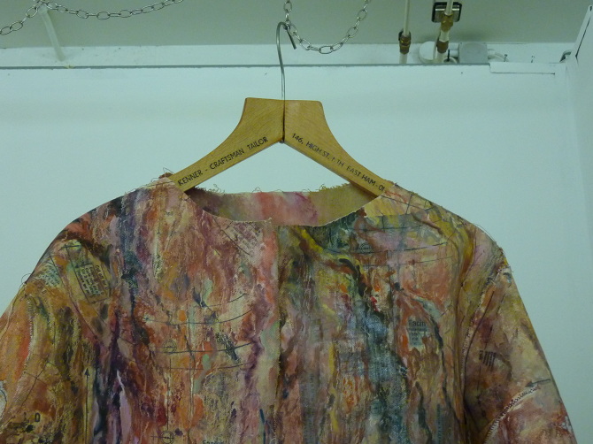 Blurred Boundaries — Garment hanging on a wooden hanger — patterned with maps and text