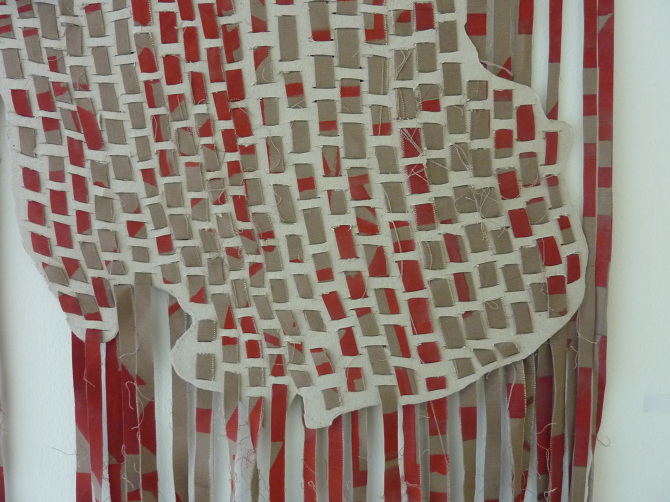 One divided by 193+ — Map-like form woven from tan and red strips, loose ends hanging